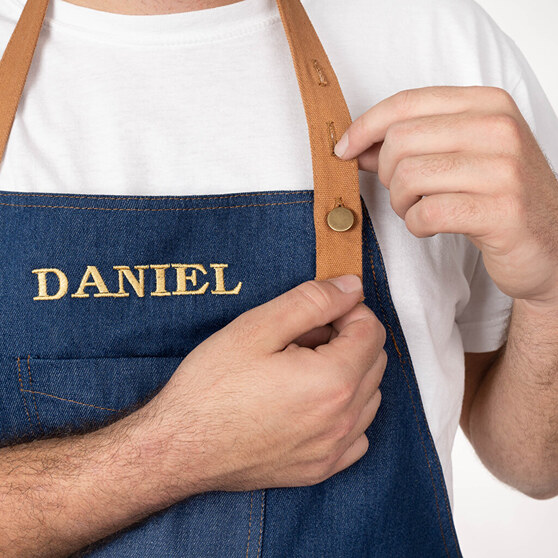 Detail denim keukenschort met geboruurde naam Detail denim keukenschort met geboruurde naam